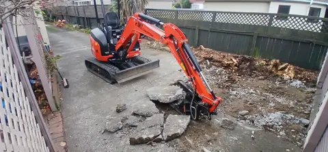 Digger breaking out a failed concrete driveway