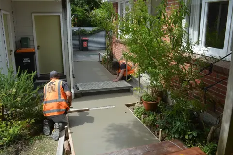 Concreter finishing a new concrete path to a back door in Palmerston North