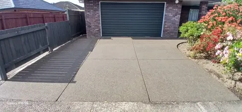 Exposed aggregate concrete driveway beside a brick-fronted garage in Palmerston North